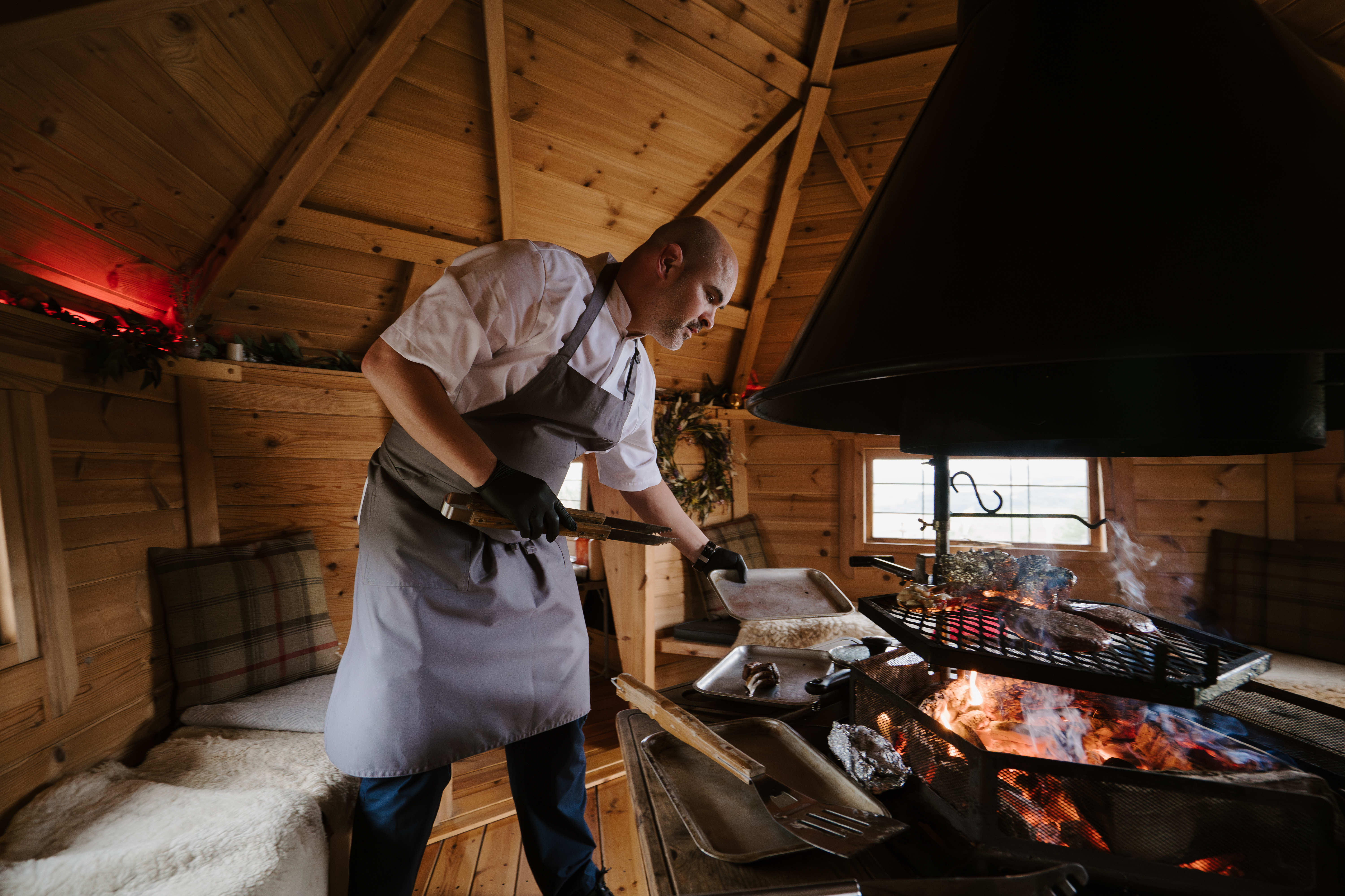 A chef cooking inside a quaint barbecue hut.