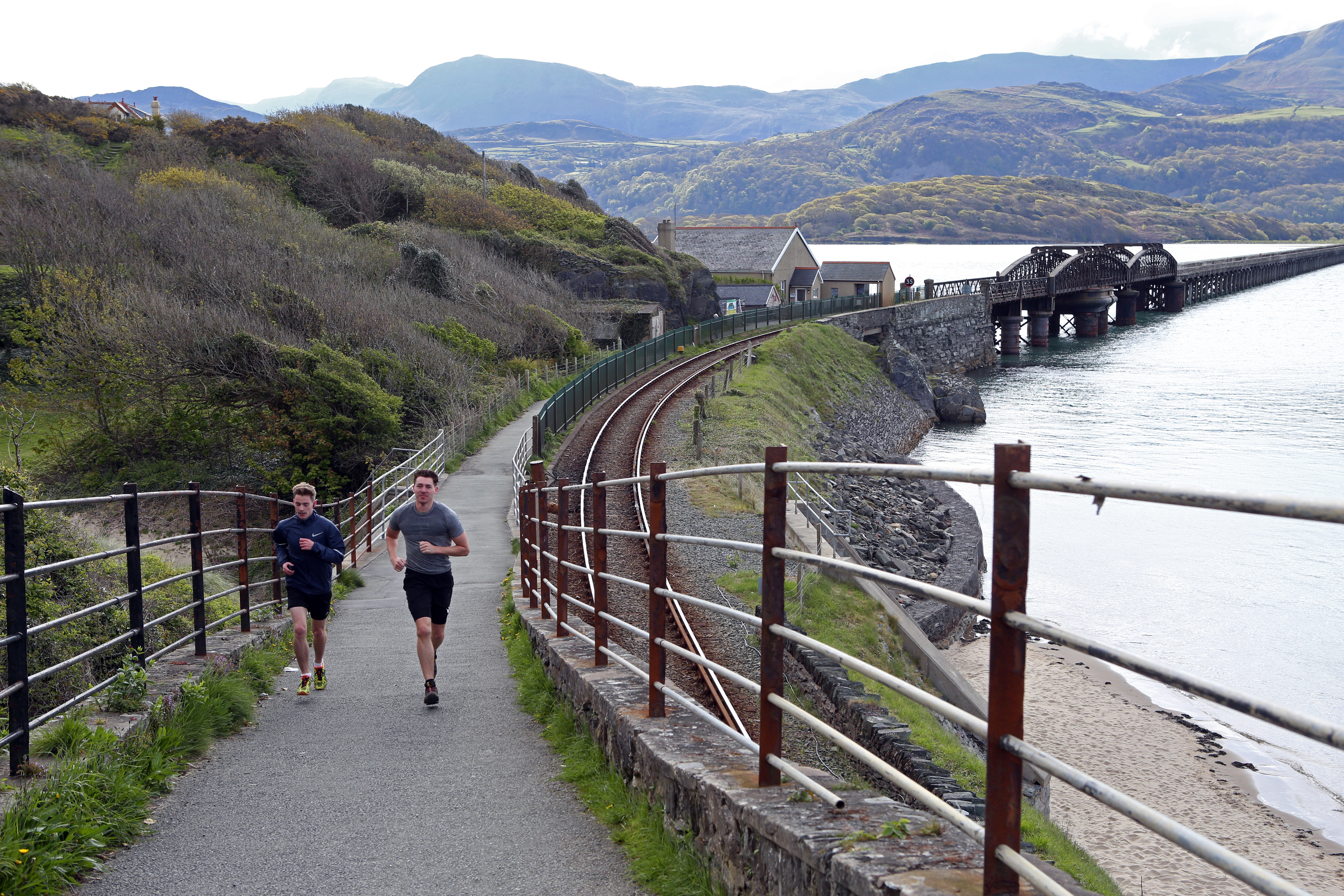Two people running along a coastal path in Wales