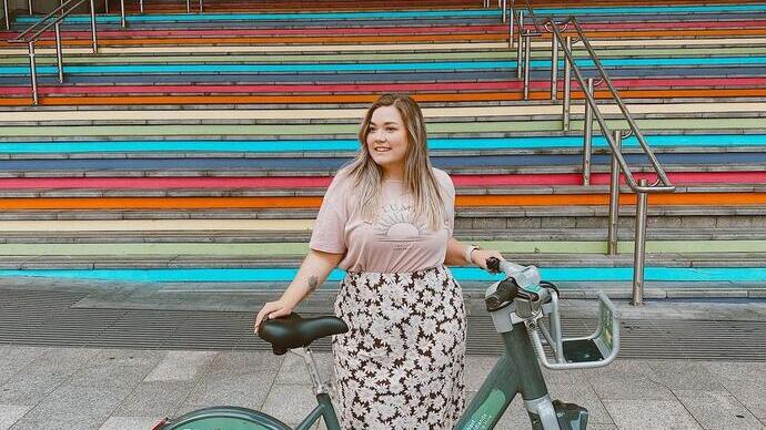 Woman standing in front of steps with green coloured bicycle