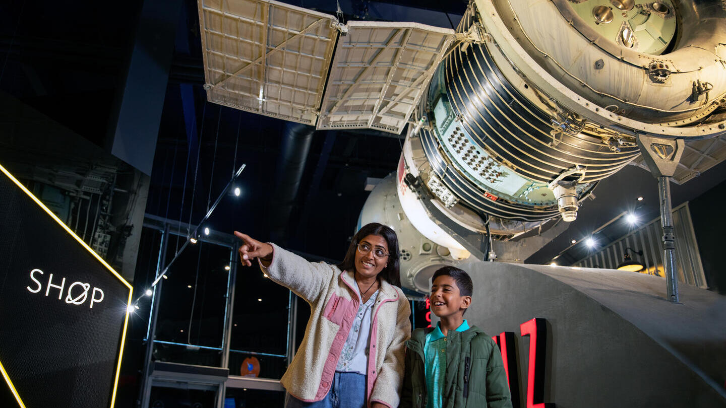 Una donna e suo figlio guardano una mostra spaziale