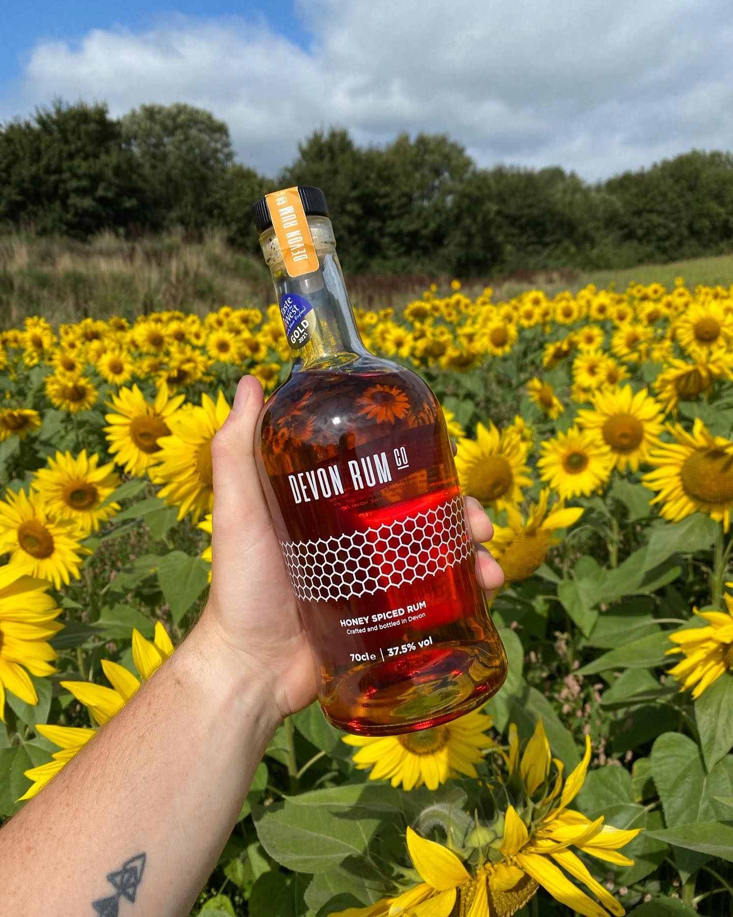 Summer- A person holding a bottle of rum at Quince Honey Farm