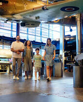 Family of four walking beneath a biplane on display