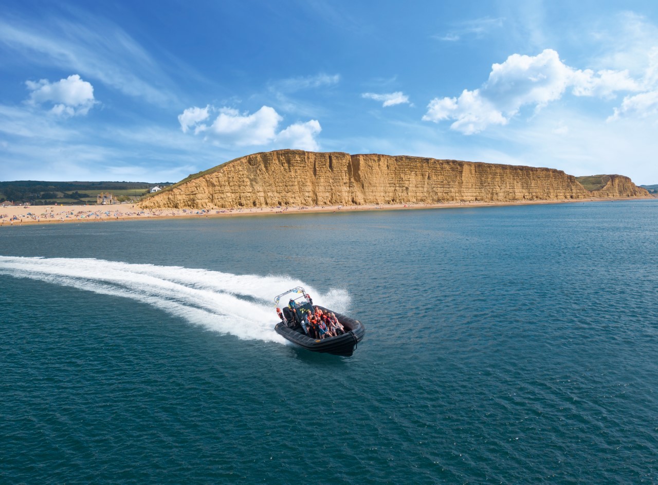 A speedboat carrying a group speeding through the ocean of Lyme Bay