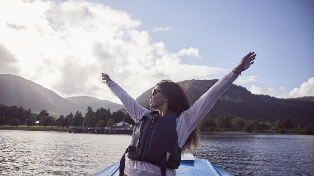 امرأة تمد ذراعيها على متن قارب في بحيرة