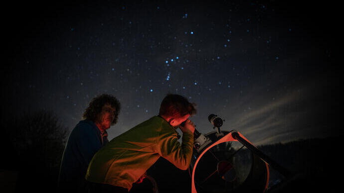 Child stargazing through telescope