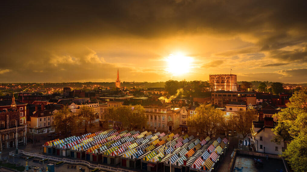 Aerial view of a city centre showing colourful market stalls at sunrise
