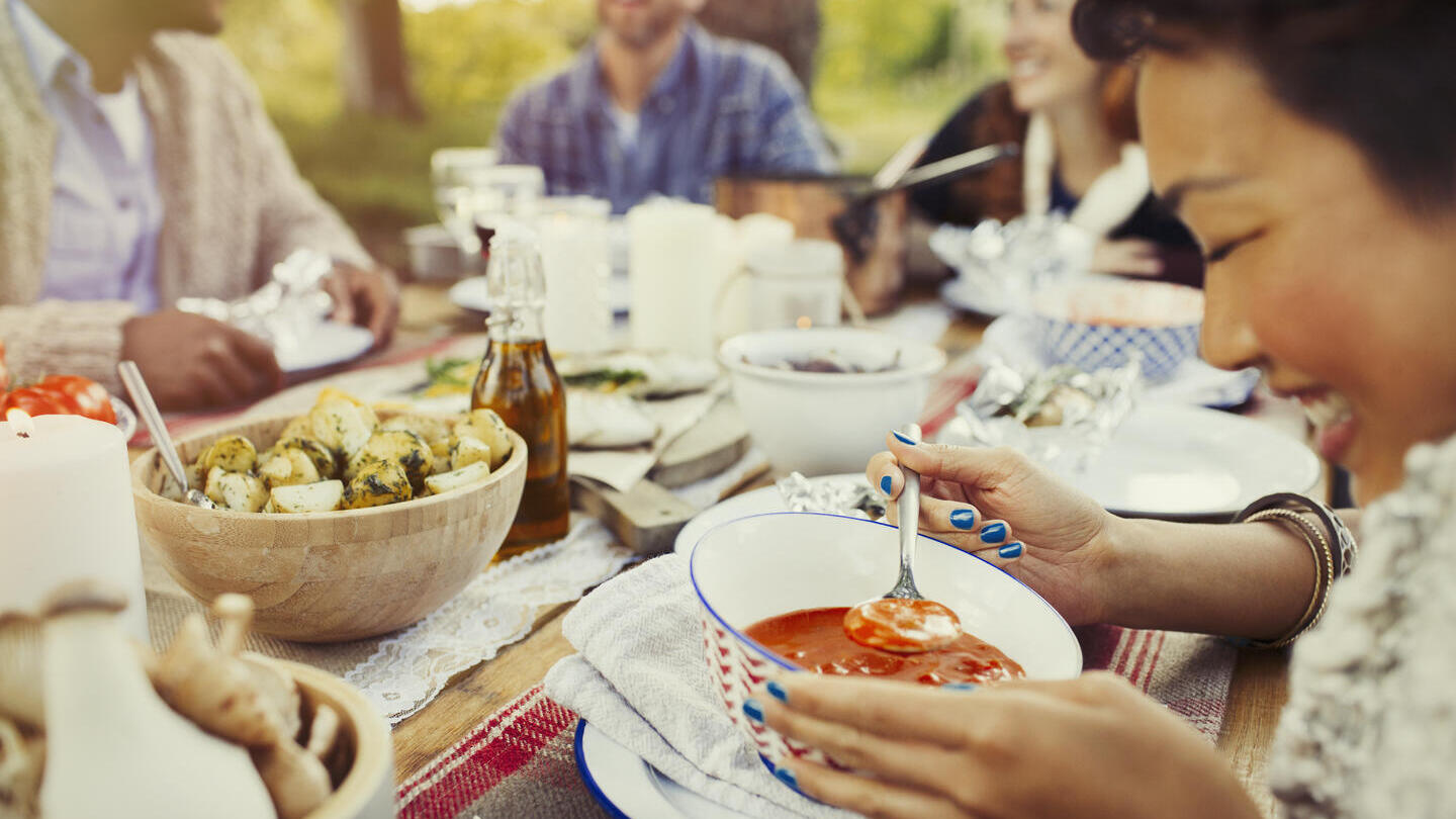 People eating a meal outdoors at a large table