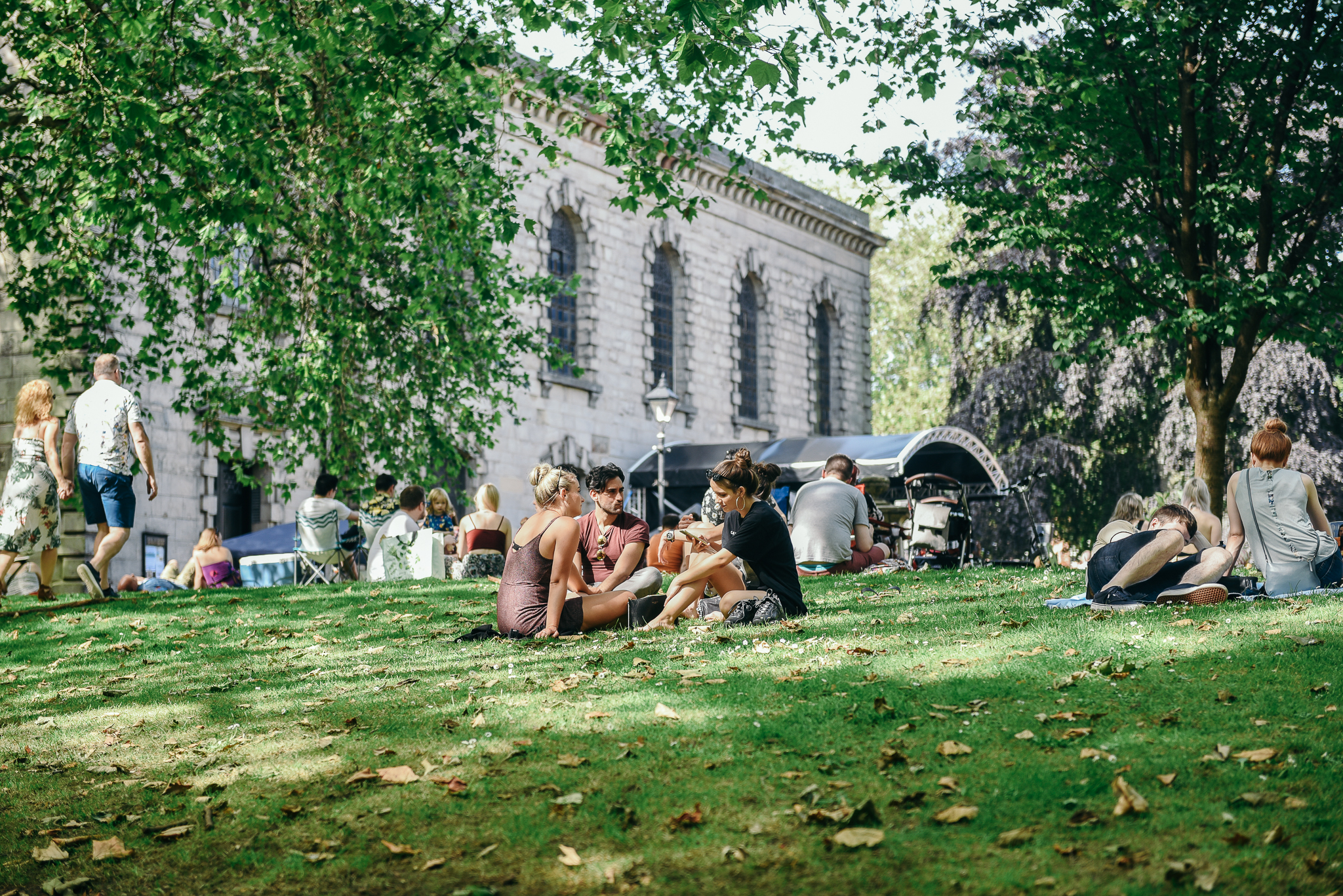 Groups of people sat on a grassy slope in the Jewellery Quarter in Birmingham