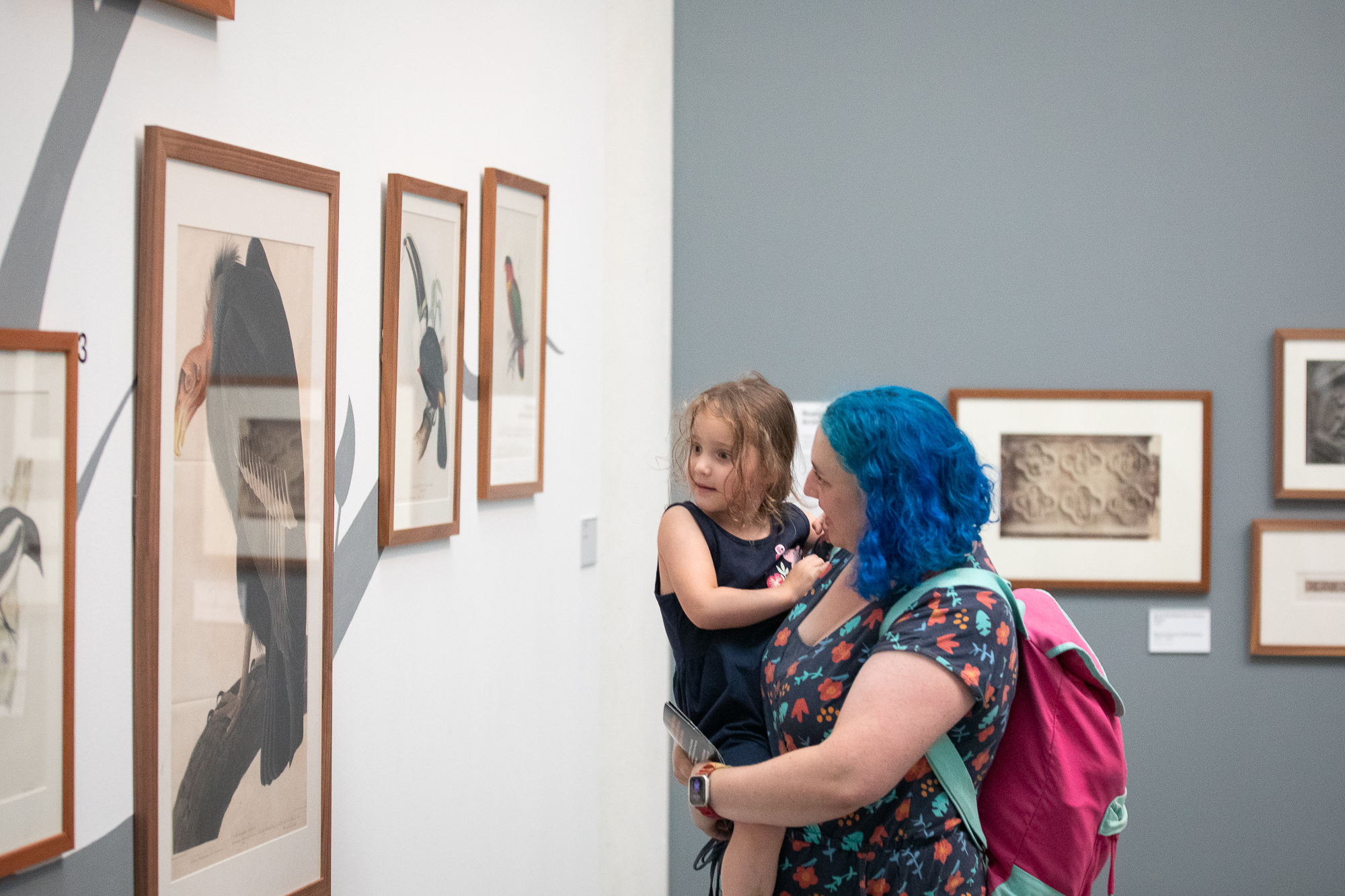 A woman carrying a child, looking at artworks in the Ruskin Collection at the Millennium Gallery in Sheffield