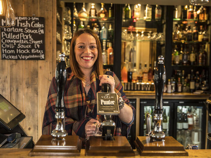Woman serving drinks behind the bar in a pub