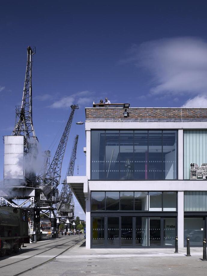 The main entrance to a city museum, next to a crane on the harbourside.