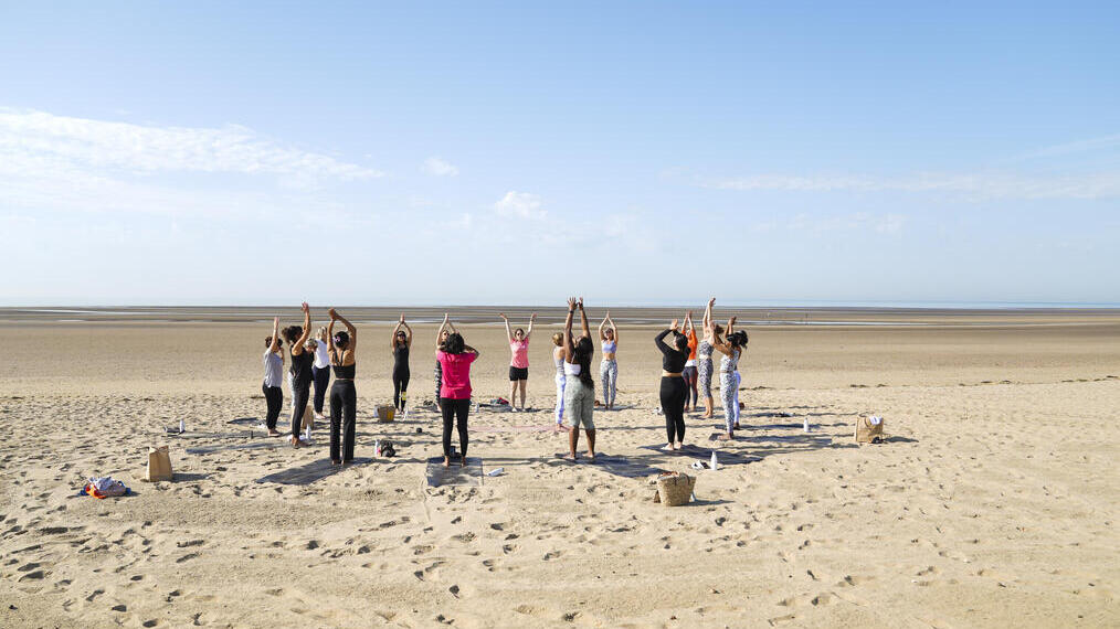 A group of adults in a circle on the beach practising yoga at The Gallivant