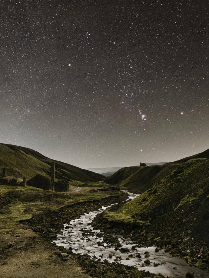 A stream winding through the mountains under a starry sky.