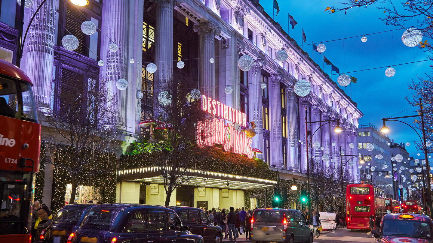 Ein großes Kaufhaus, geschmückt mit Weihnachtsbeleuchtung, in einer belebten Straße