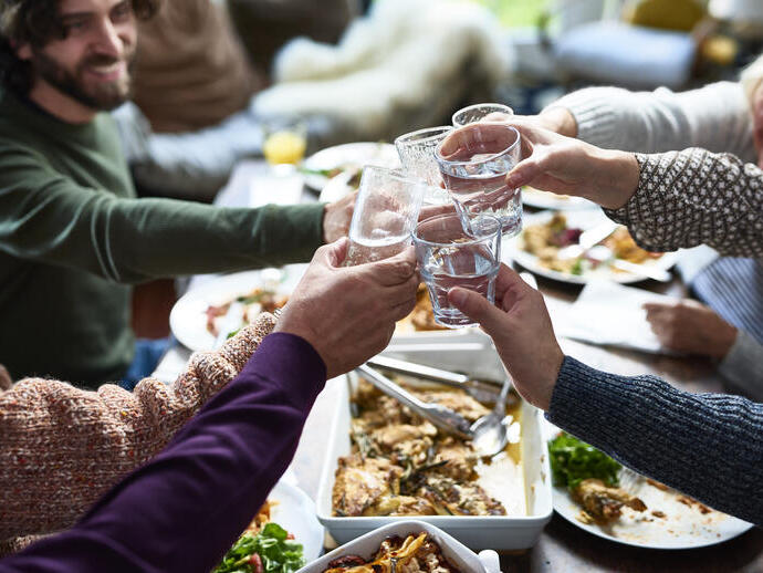 Eine Gruppe von Menschen, die bei einem Mittagessen mit Getränken anstoßen