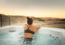 A woman in a hot tub outdoors overlooking the countryside.