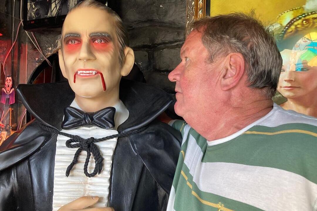 Man looking closely at wax model of Dracula, part of the Dracula Experience