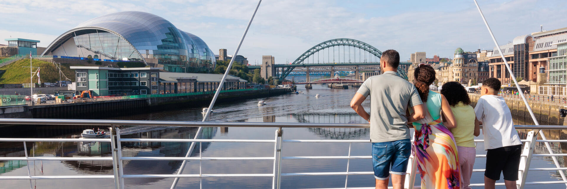 Family standing on a bridge overlooking a city river