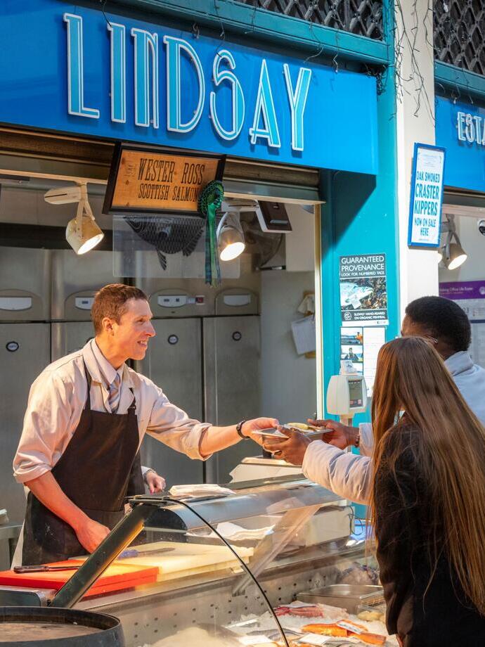 A fishmonger serving a customer at Grainger Market in Newcastle