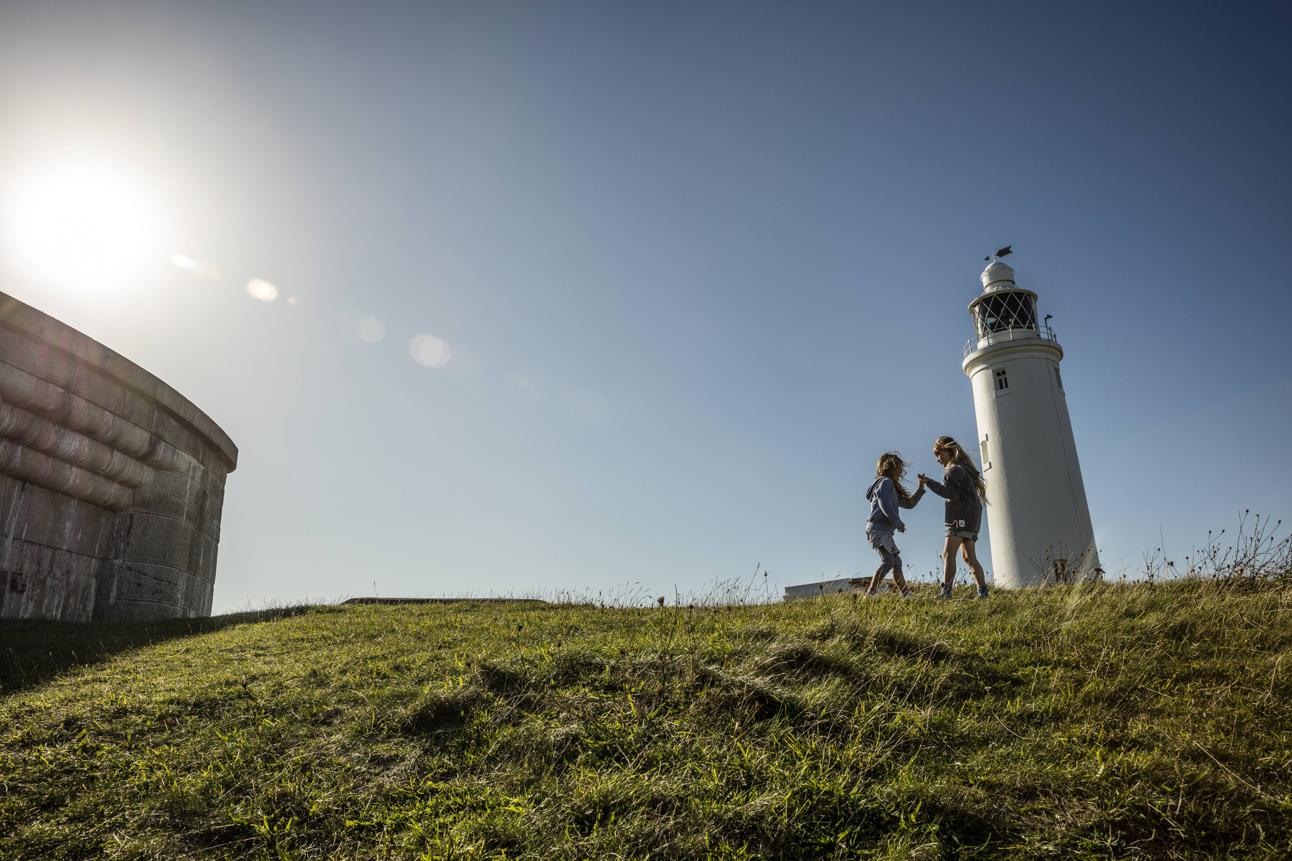 Two children playing in open space by a lighthouse