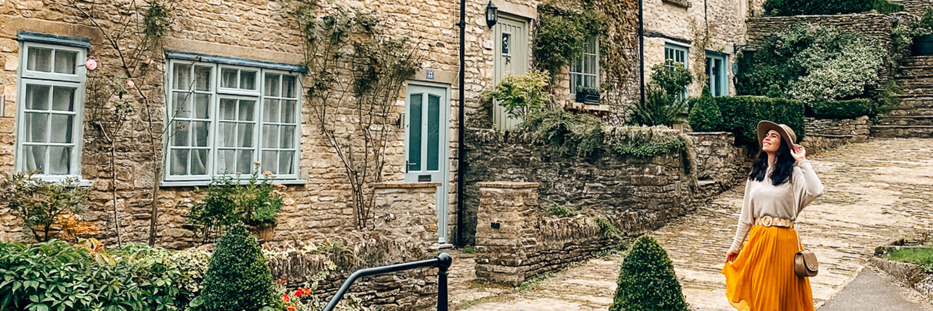 A woman in a hat walks down a street in a quaint village