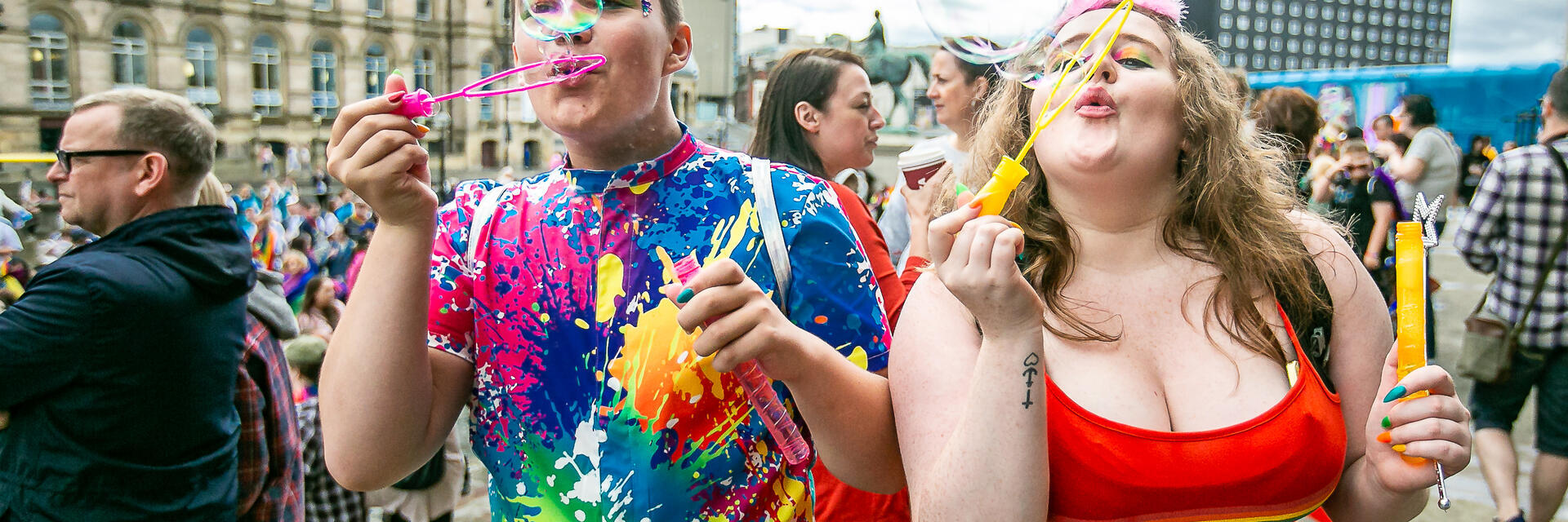 Deux personnes célébrant la Liverpool Pride en soufflant des bulles vers l'appareil photo