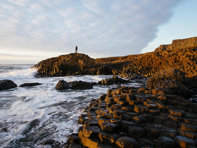 Man standing on a rock formation on the edge of the sea