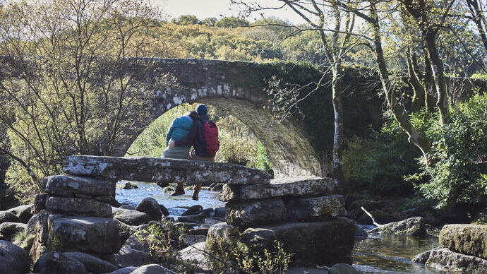Couple assis sur un pont en pierre au-dessus d'un ruisseau