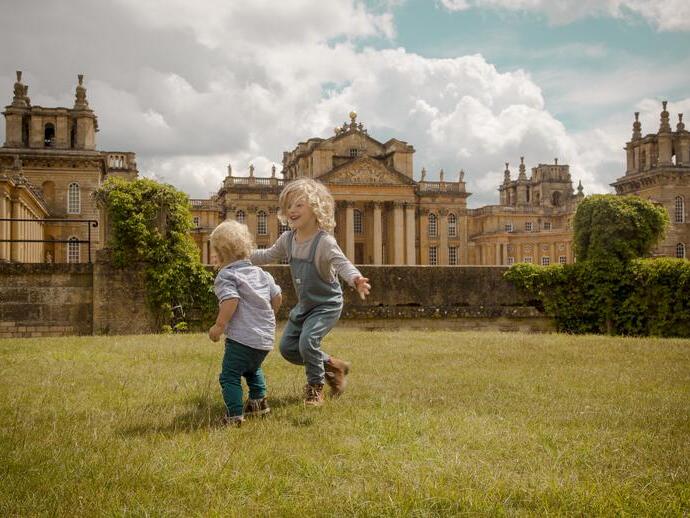 Two children play on the lawn in front of a palace
