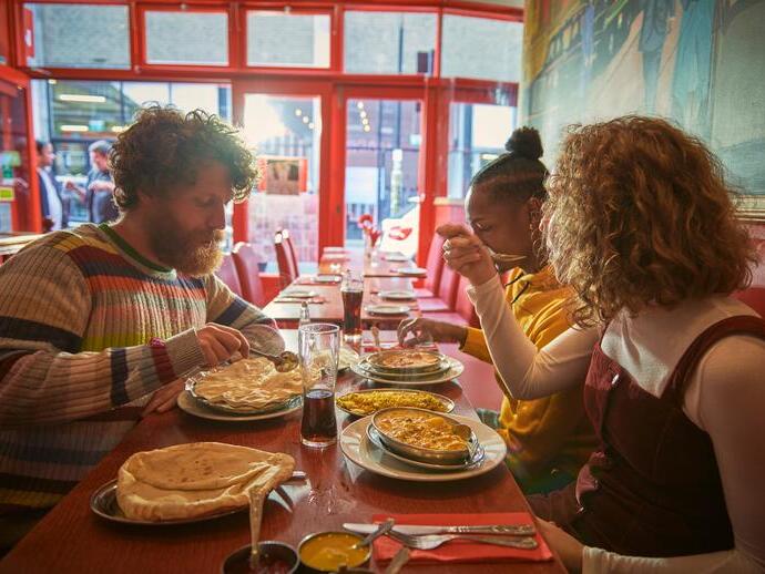 Dos hombres y una mujer comiendo en un restaurante