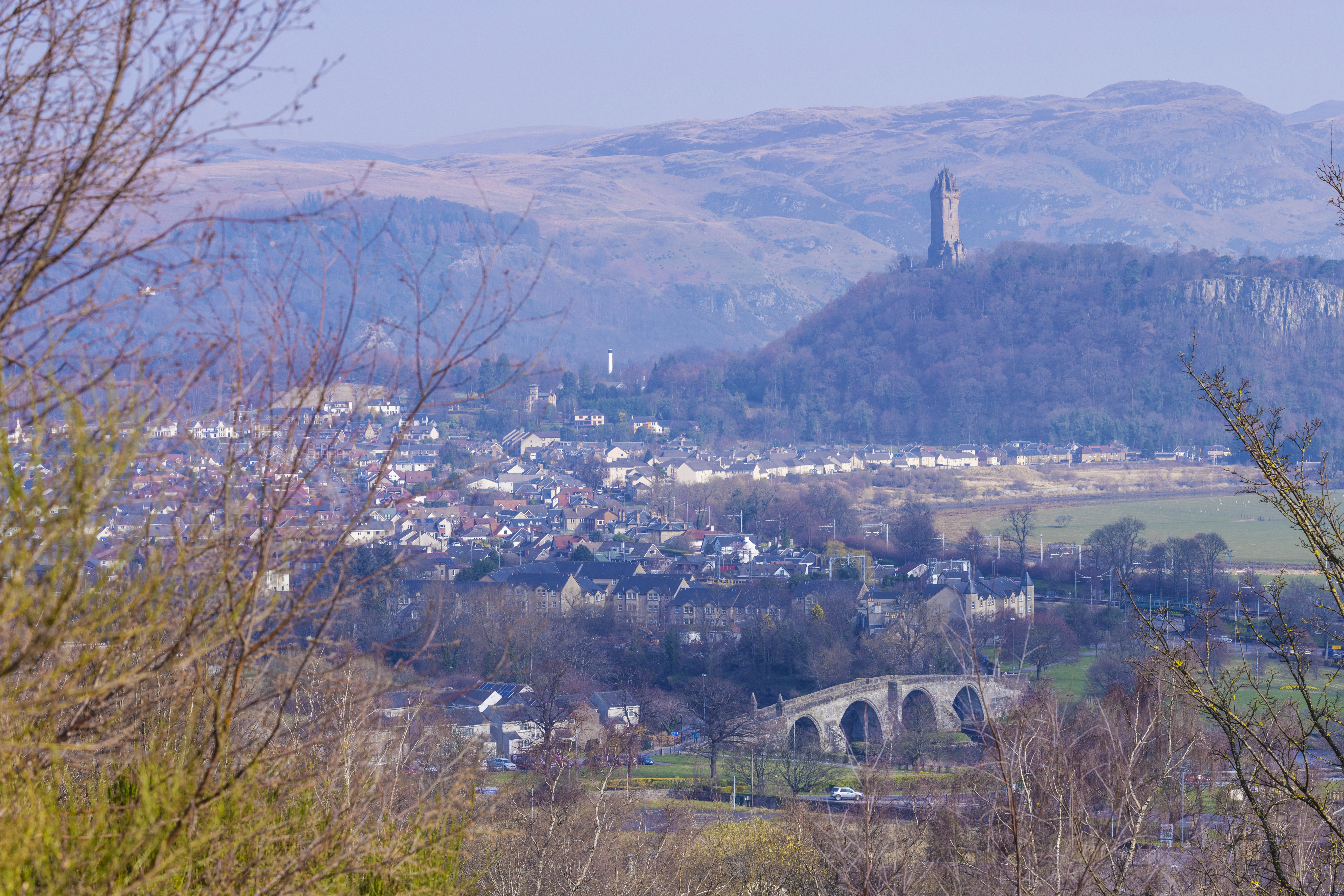 Luftaufnahme einer Stadt mit einer Statue auf einem Hügel im Hintergrund.