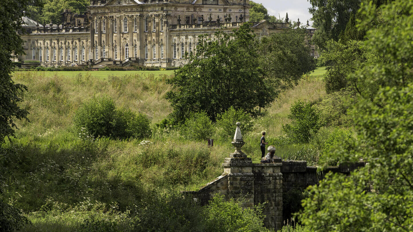 منزل ريفي كبير محاط بالأشجار مع جدول في المقدمة