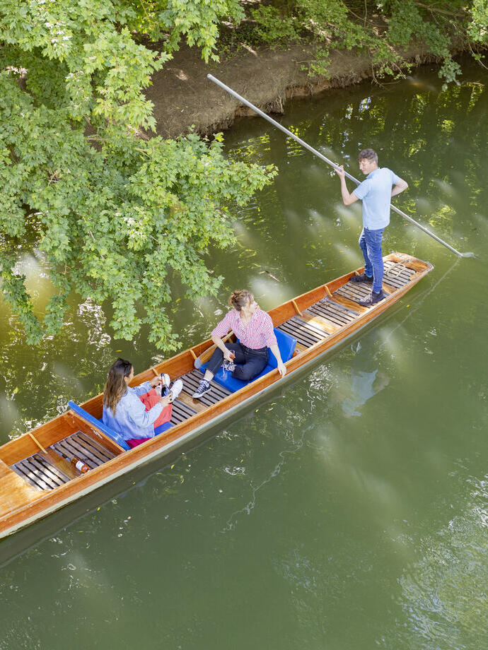 Two women sit on a punt on a river