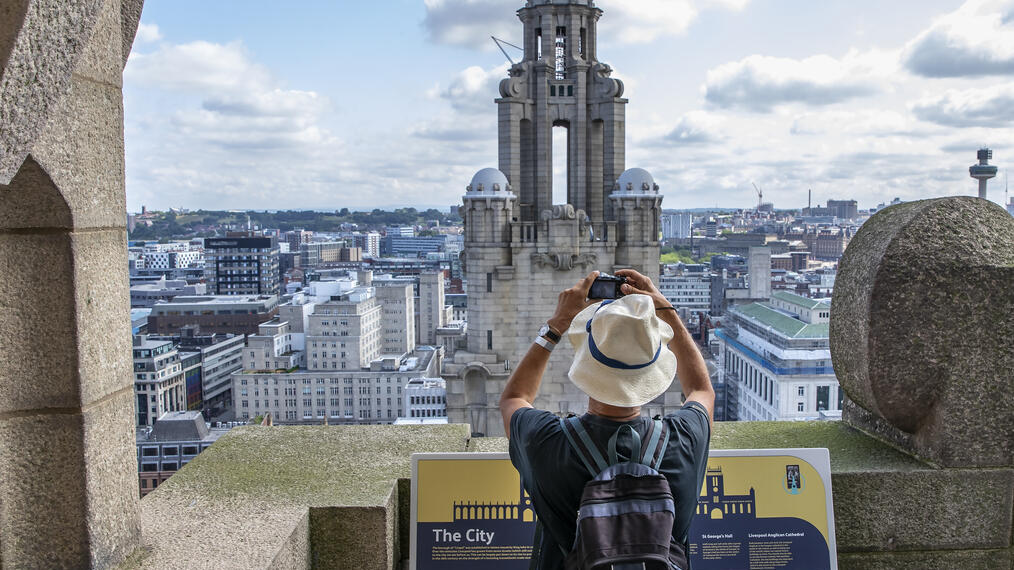 Man photographing a tower in the skyline from a rooftop viewing platform