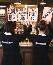 Due cameriere del Devonshire Balham Public House con cartelli che pubblicizzano biglietti gratuiti per il Sei Nazioni di rugby