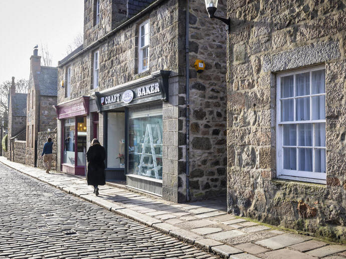 People walking along a traditional cobbled British high street.