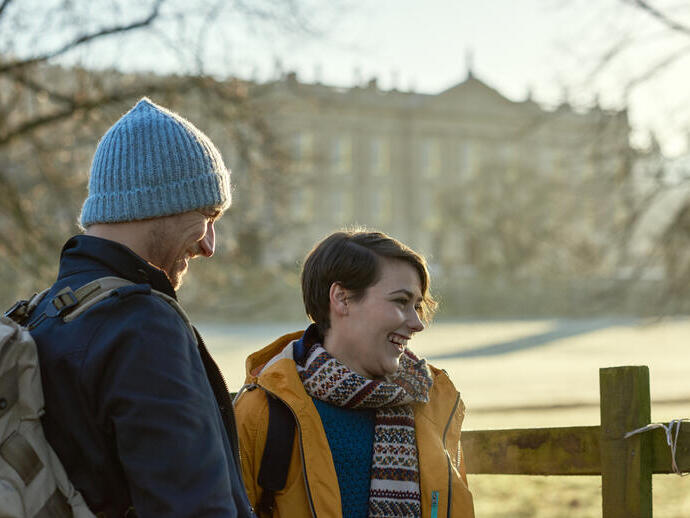 Couple smiling and standing in winter sunshine in front of a country house