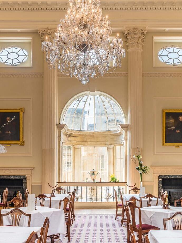 An internal view of the period dining room with tables laid for four and a large chandelier at an elegant upmarket restaurant.