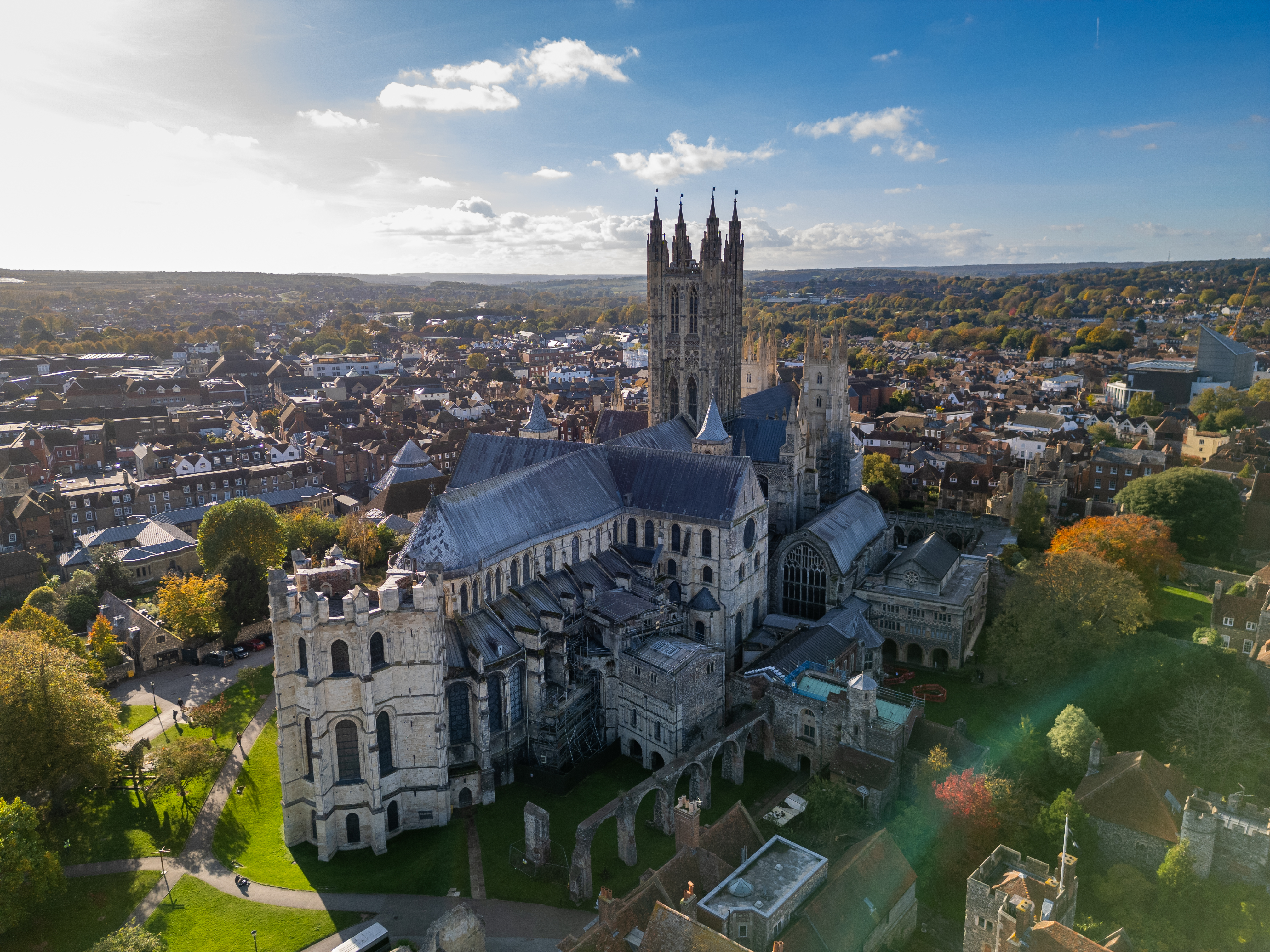 Aerial view of cathedral with tall towers surrounded by autumnal trees