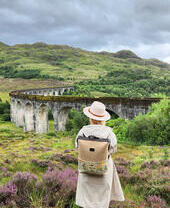 A woman standing in the countryside overlooking a viaduct.