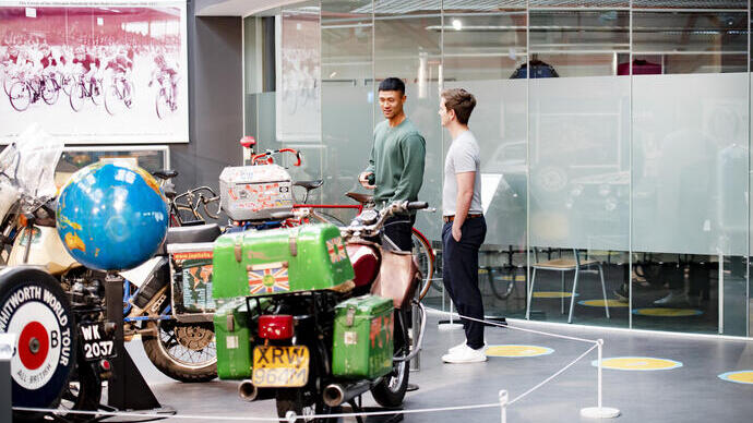 Two men looking at an exhibit of motorbikes in a museum.