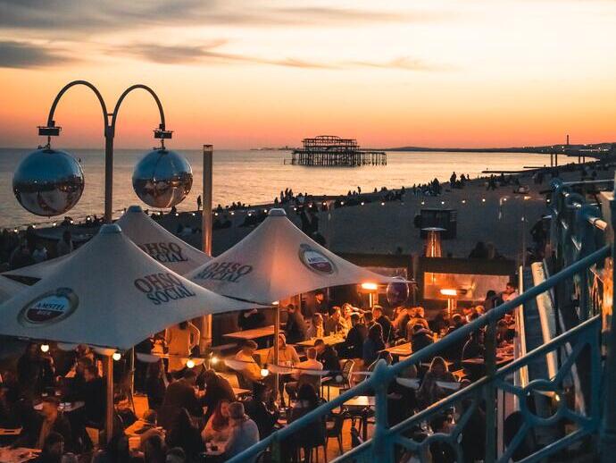 People enjoy drinks at a bar on the seafront at sundown