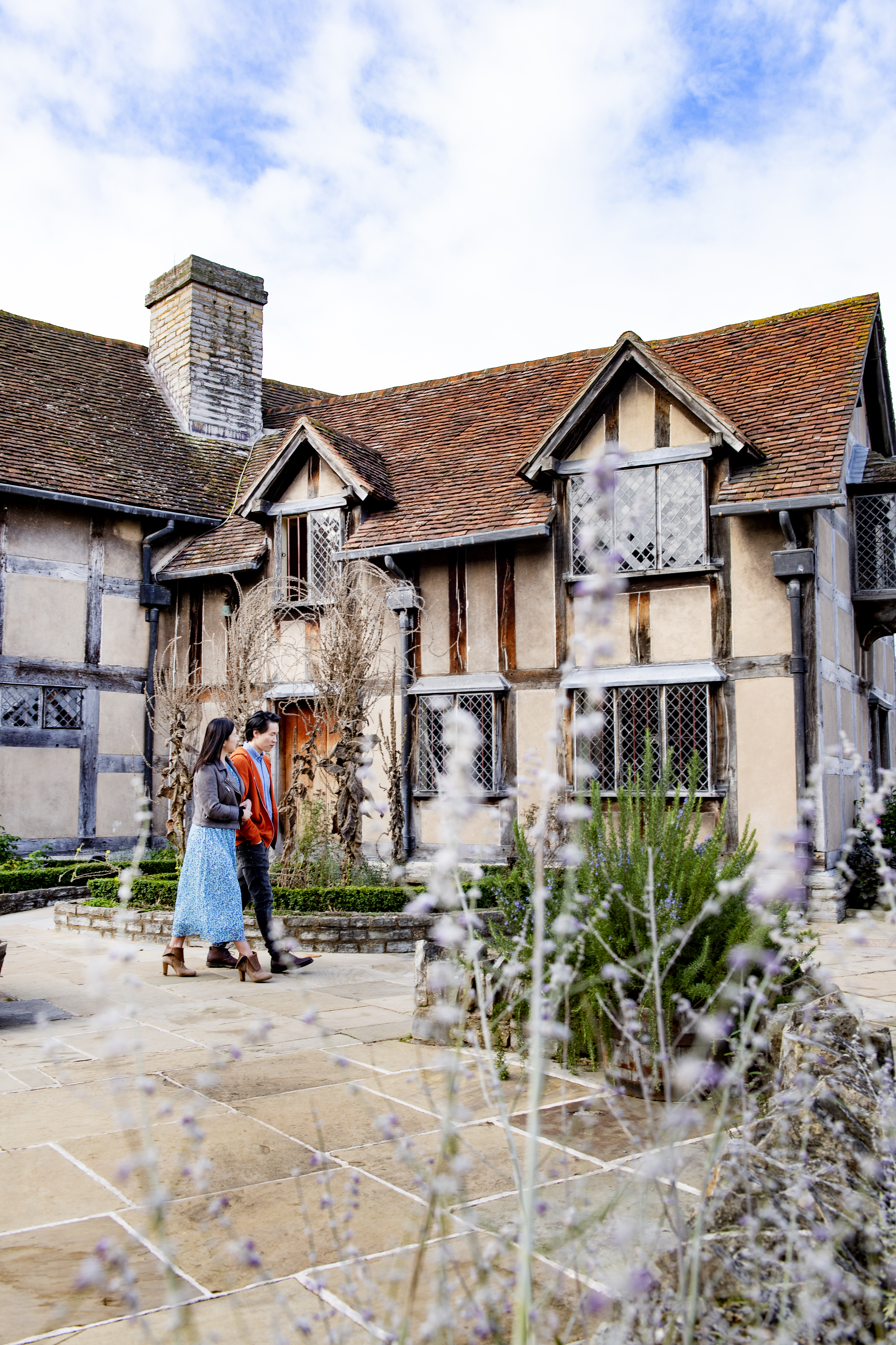 Un homme et une femme marchant devant une maison Tudor
