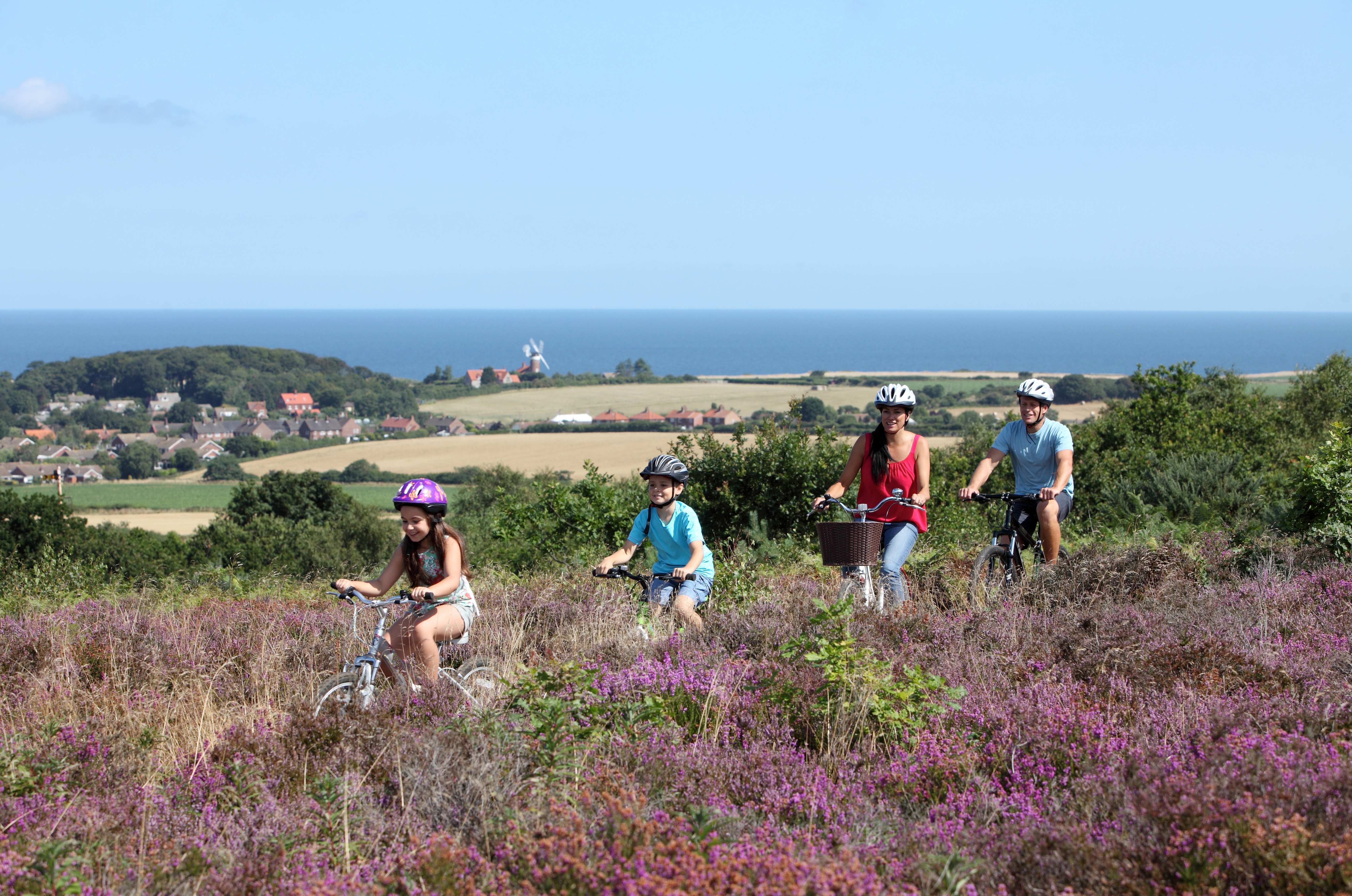 A family cycling along a path in Kelling Heath