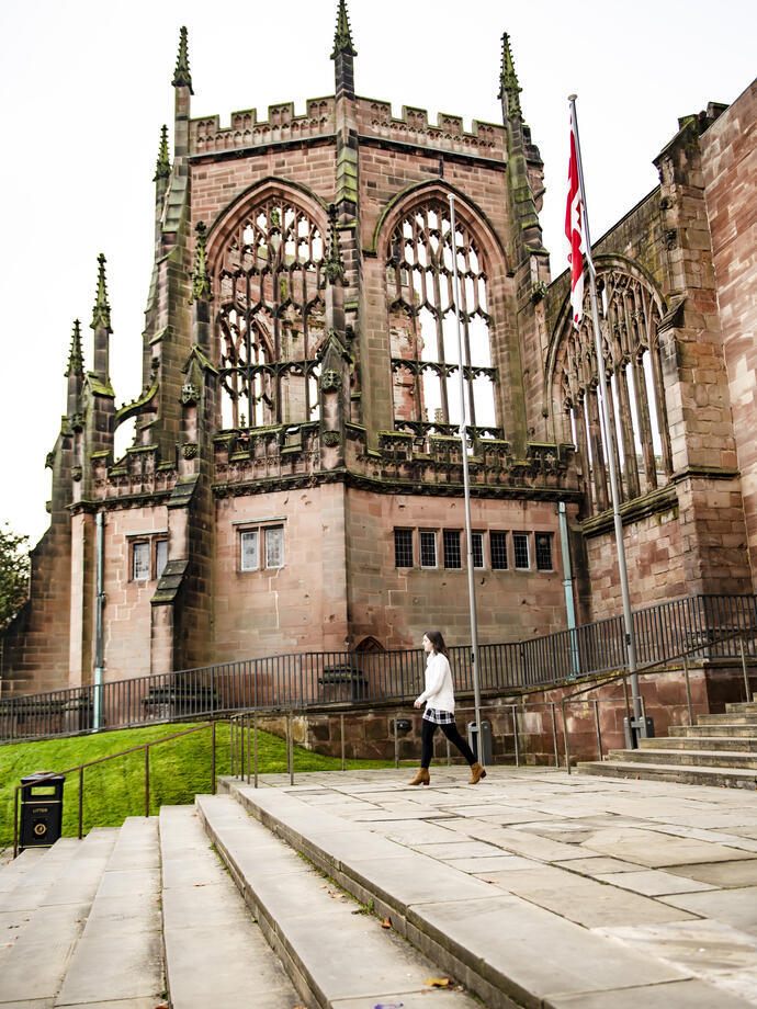 Woman walking down some steps by some cathedral ruins