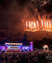 Vista del escenario principal del evento Hogmanay de Edimburgo, con fuegos artificiales al fondo