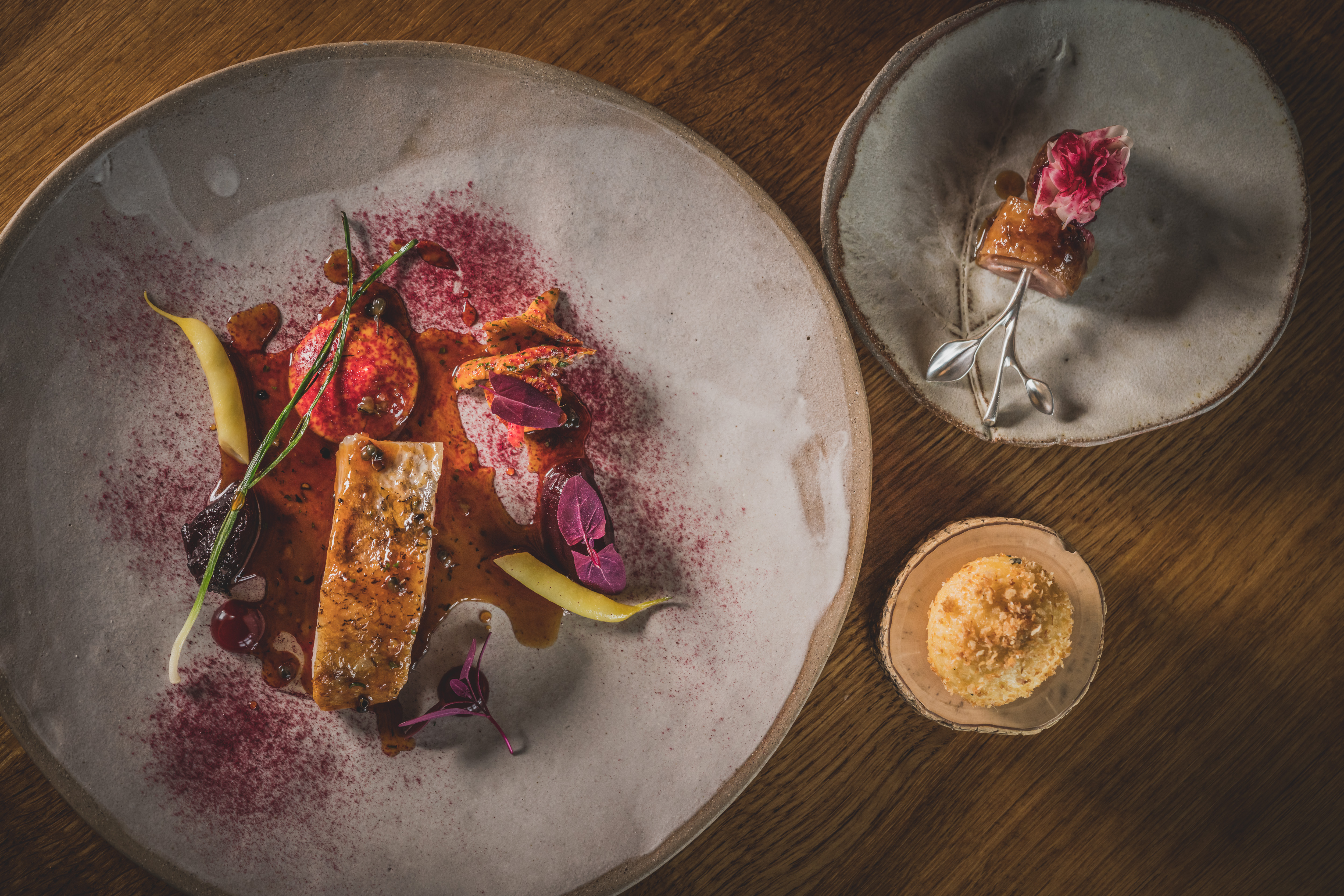 Three different sized plates of colourful food served on rustic grey crockery