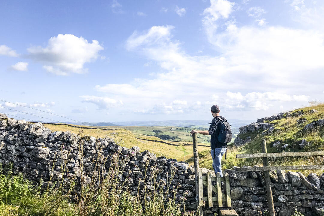 Mann steht auf einem Steg über einer Steinmauer und betrachtet die Landschaft
