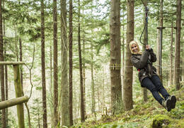 Woman travelling on a zipwire among the pine trees