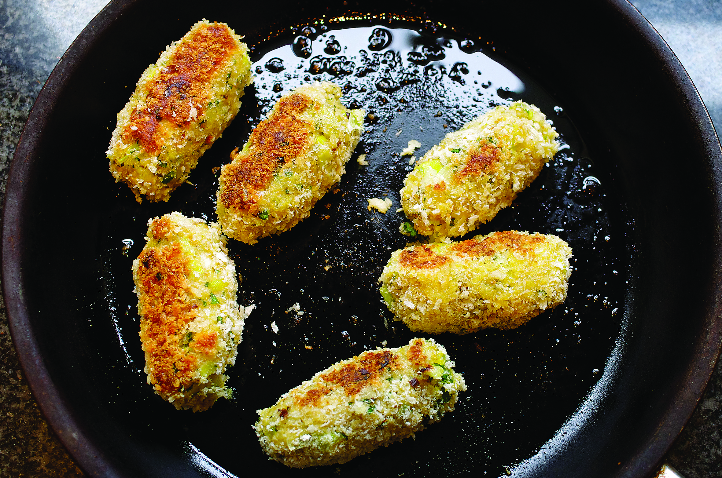 Salchichas rebozadas con pan rallado friéndose en una sartén